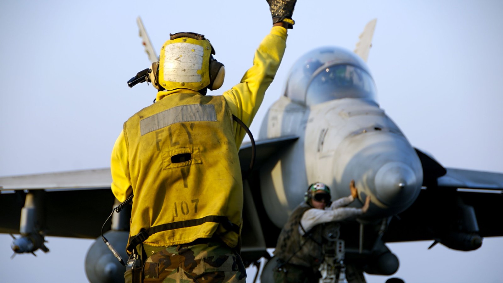 A Navy Sailor military directs an F 18 Hornet fighter aircraft around the flight deck jet aircraft carrier Derek Gordon Shutterstock