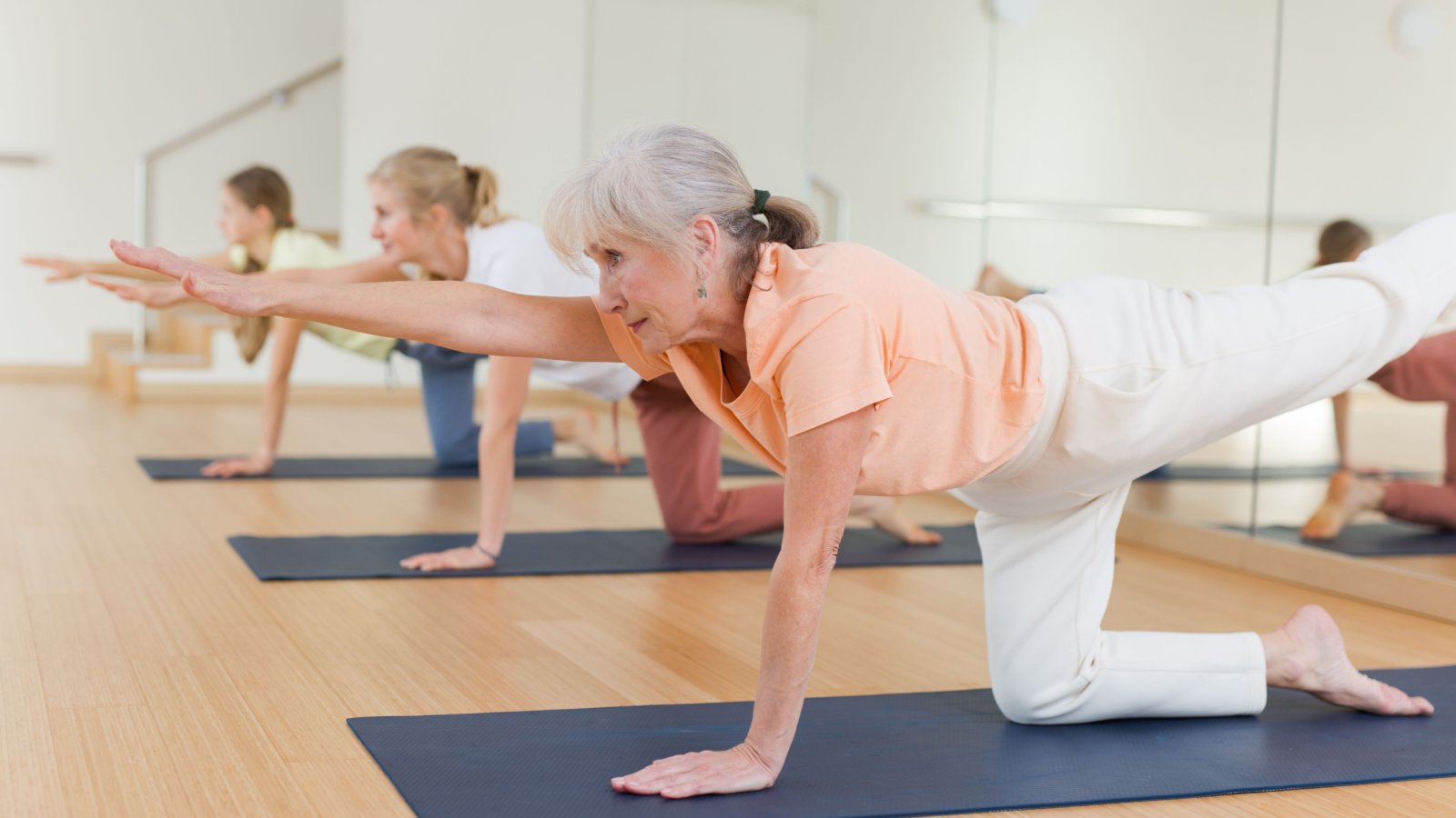 Active senior woman exercising stretching workout and incline during yoga class in fitness studio BearFotos Shutterstock