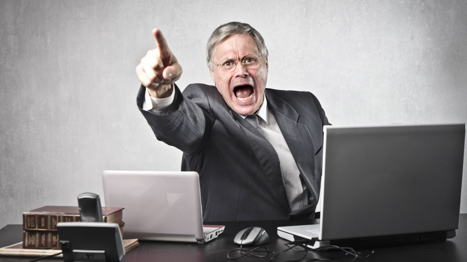 Angry senior business male sitting at his desk boss work