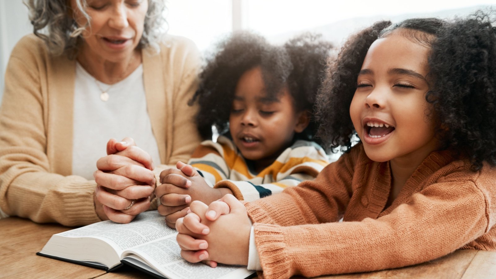 Bible worship grandmother praying with children PeopleImages.com Yuri A Shutterstock