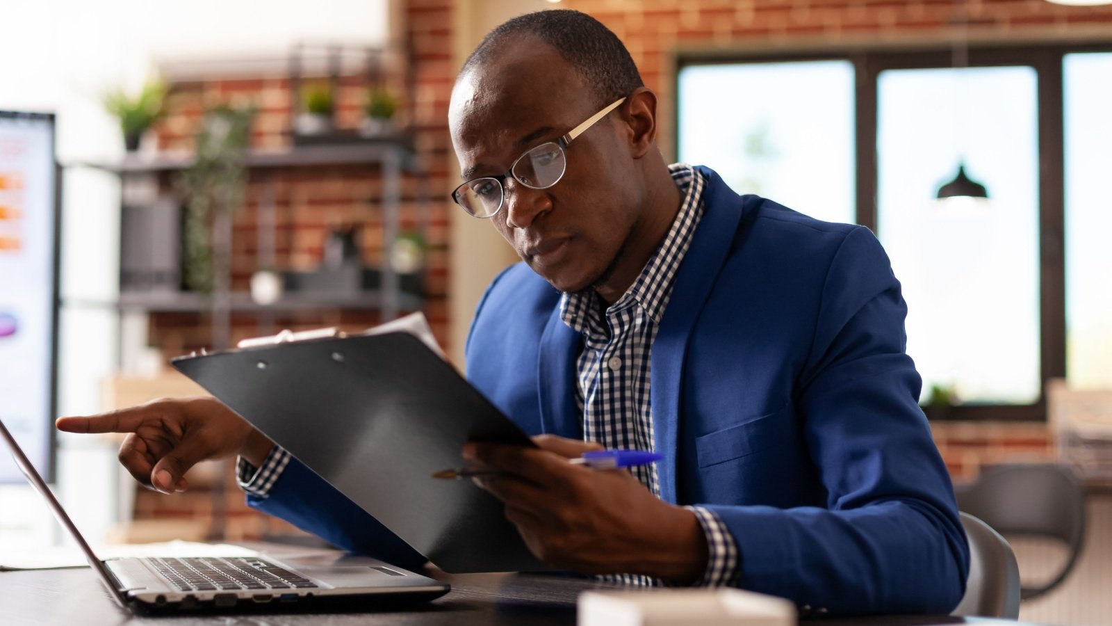 Business man looking at documents on clipboard to plan monitor document paperwork job office DC Studio Shutterstock