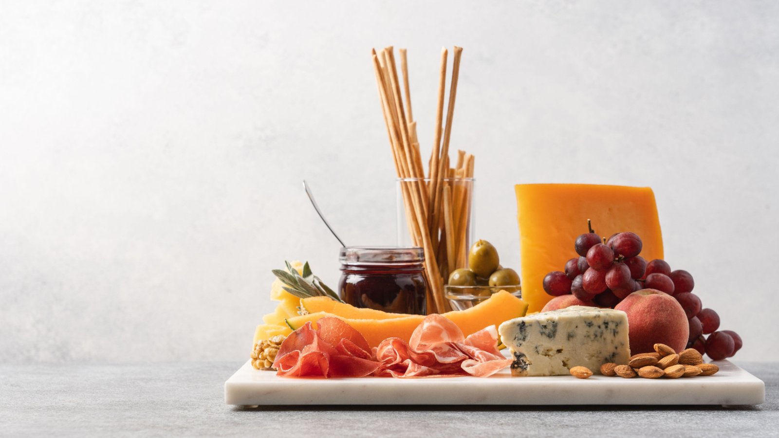 Cheese board fruit nuts olives food appetizer Anna Puzatykh Shutterstock