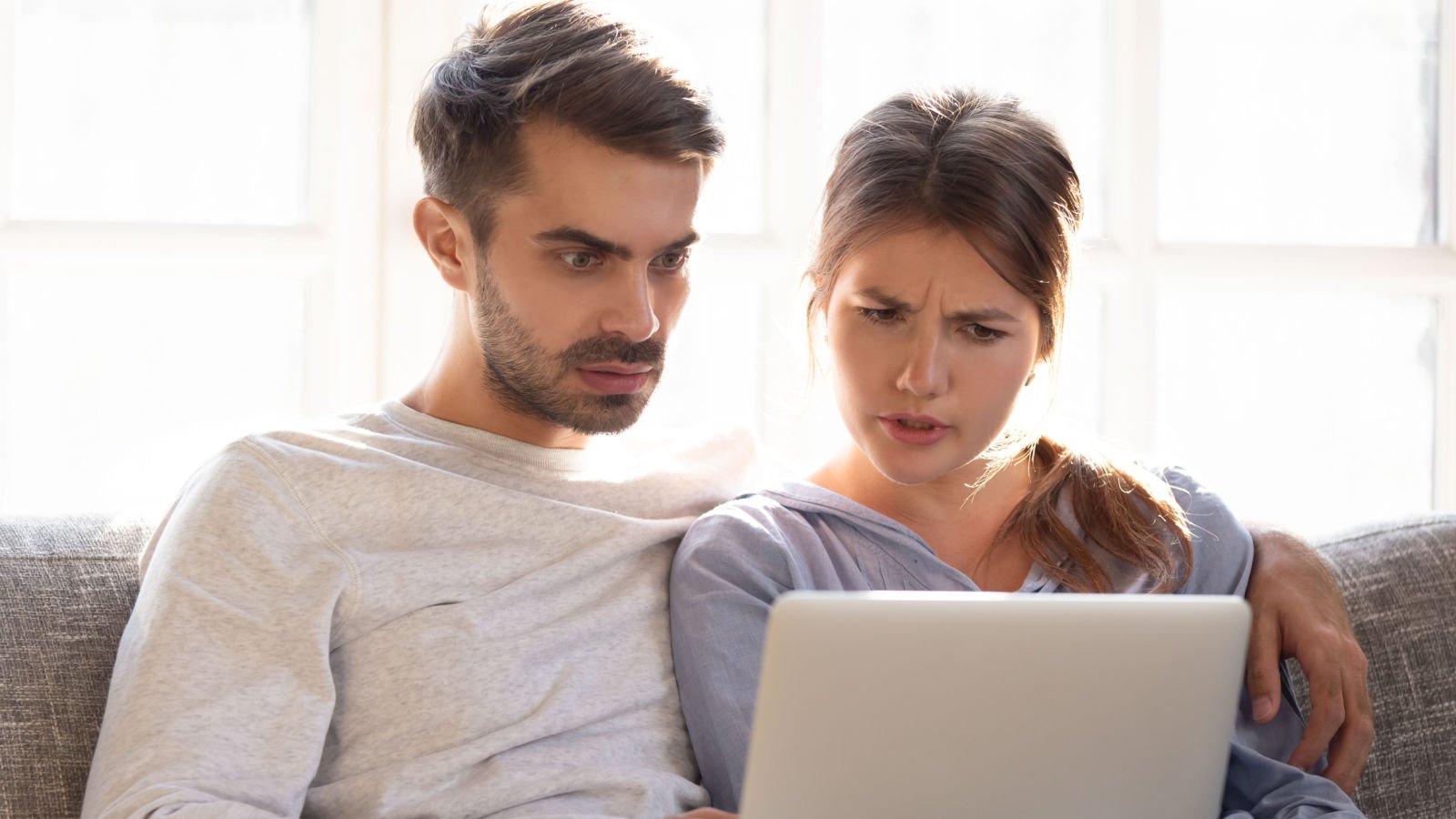 Confused baffled wife and shocked frustrated husband reading online computer together fizkes shutterstock