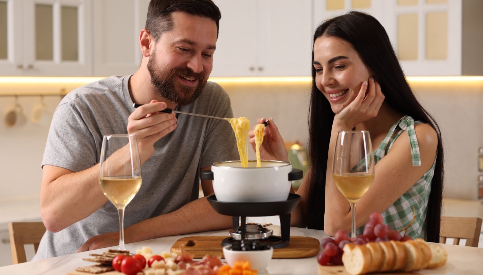 Couple eating cheese fondue with wine bread grapes and tomatoes New Africa Shutterstock