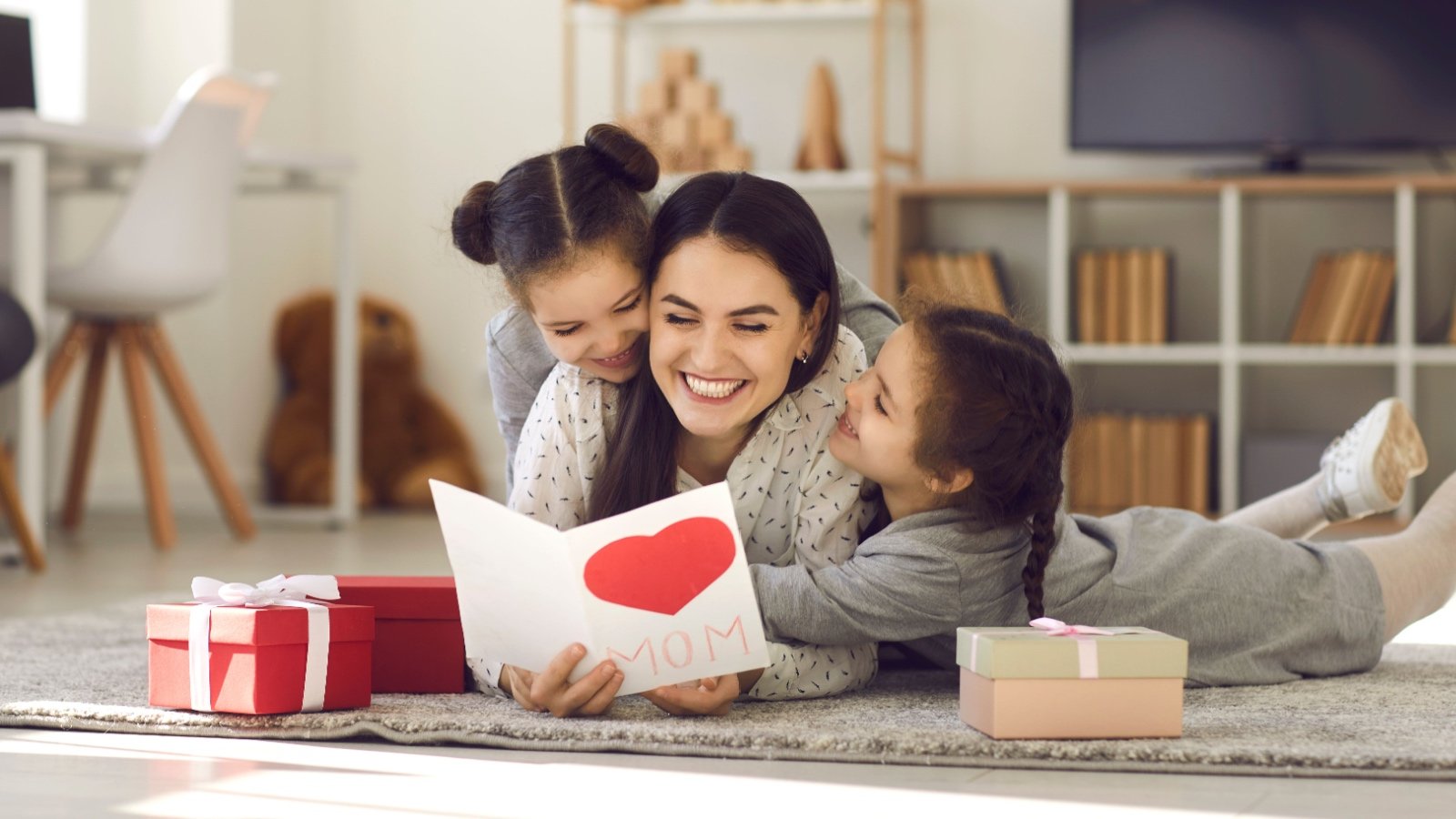 Daughters giving mom present and card Studio Romantic Shutterstock