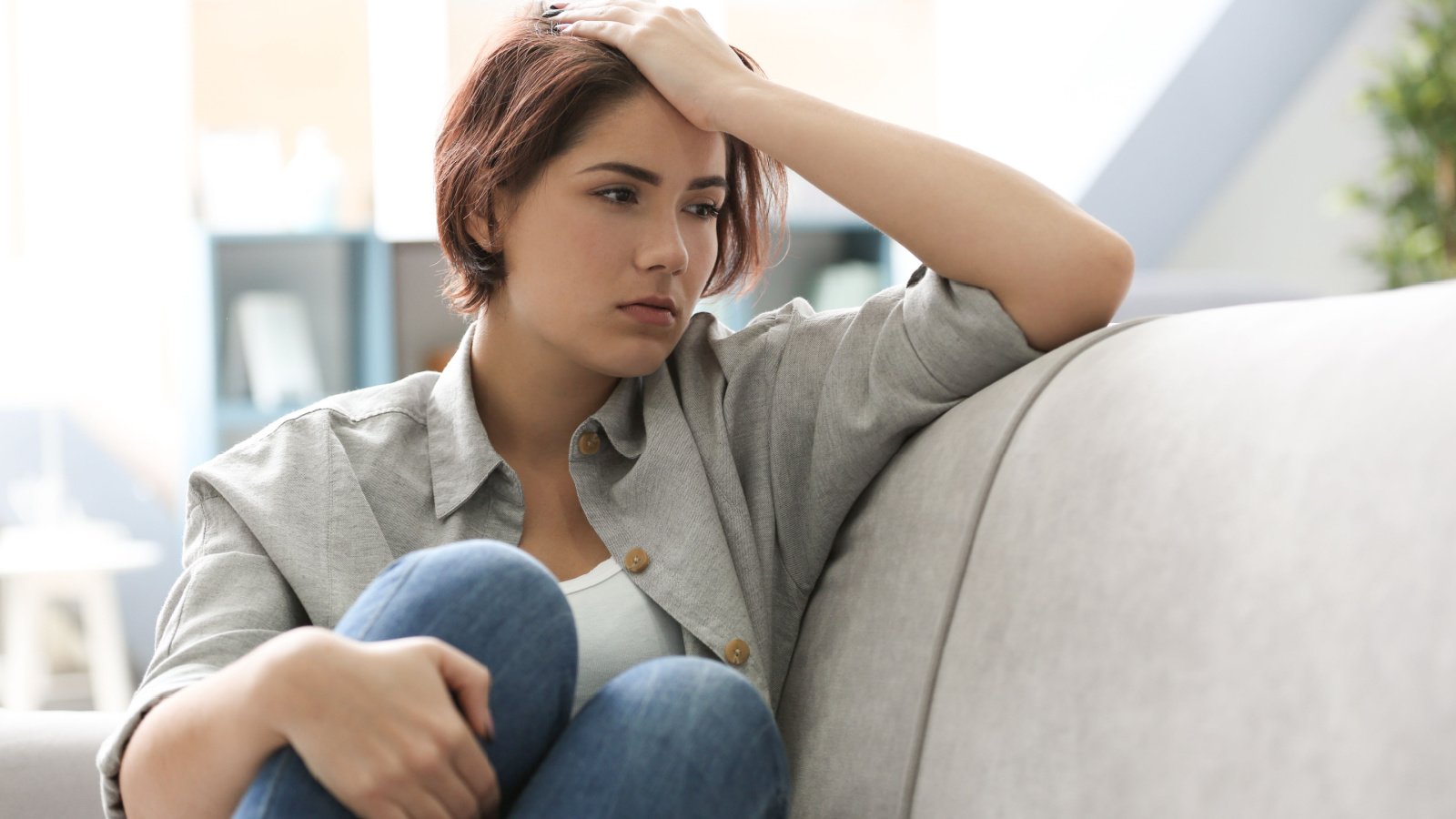 Depressed young woman sitting on sofa at home sad nervous africa studio shutterstock