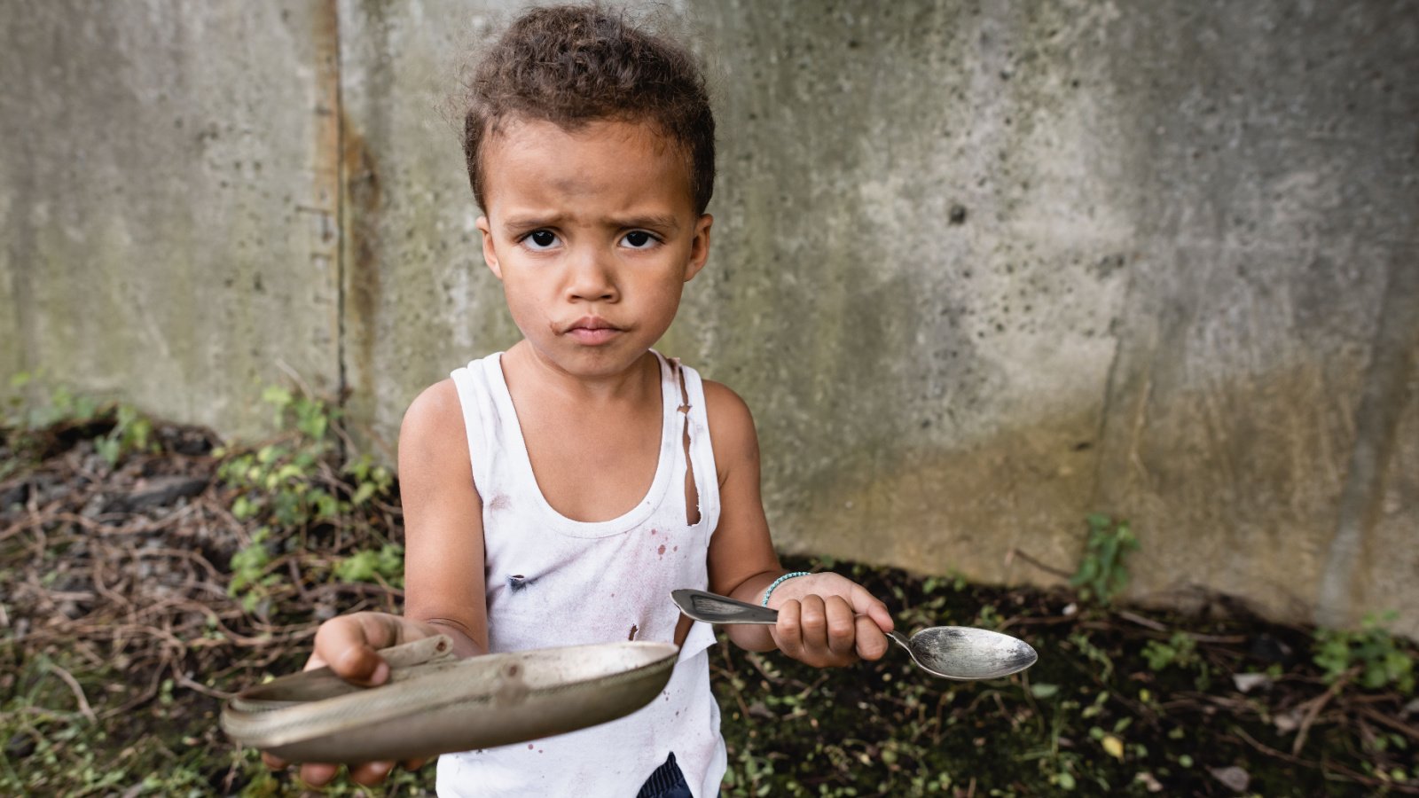 Dissatisfied african american boy holding dirty plate and spoon hungry poor POC LightField Studios shutterstock