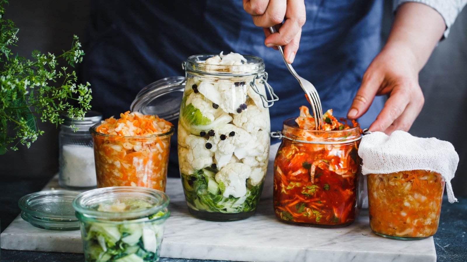 Fermented preserved vegetarian food Cabbage kimchi, broccoli marinated, sauerkraut glass jars casanisa Shutterstock