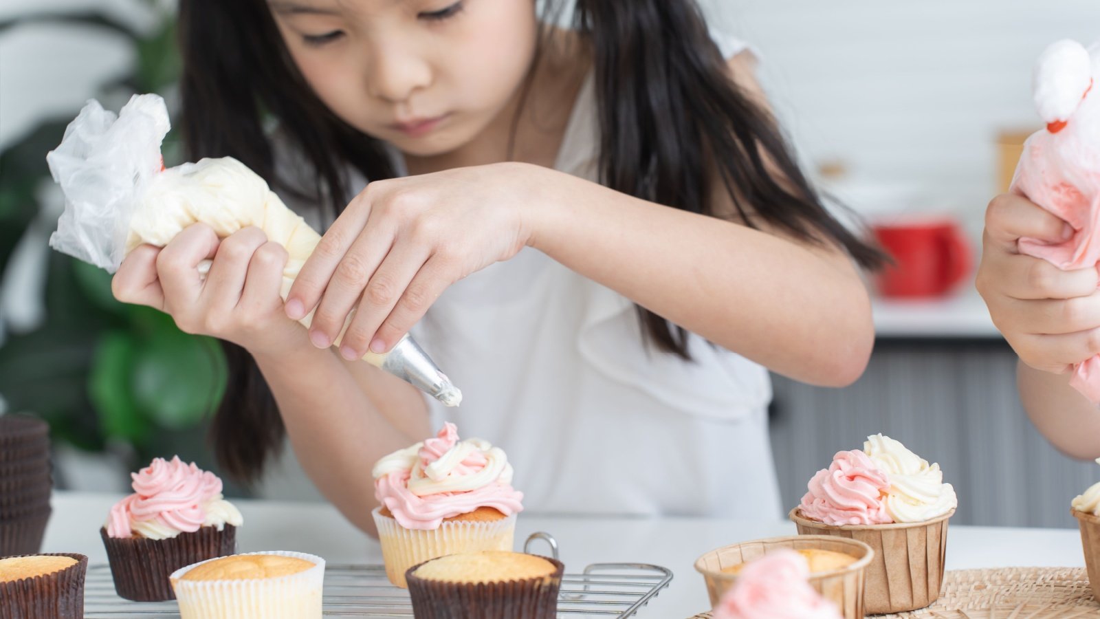 Girl child kid decorating cupcakes icing baking frosting chef kitchen birthday dessert sweets mae chaba Shutterstock