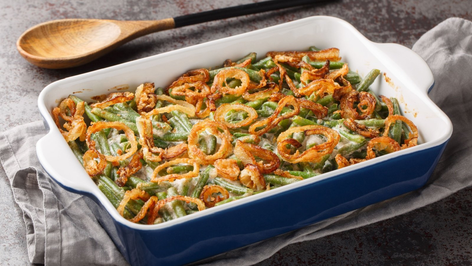 Green bean casserole with cheesy mushroom sauce and topped with crispy onions thanksgiving holiday dish AS Foodstudio Shutterstock