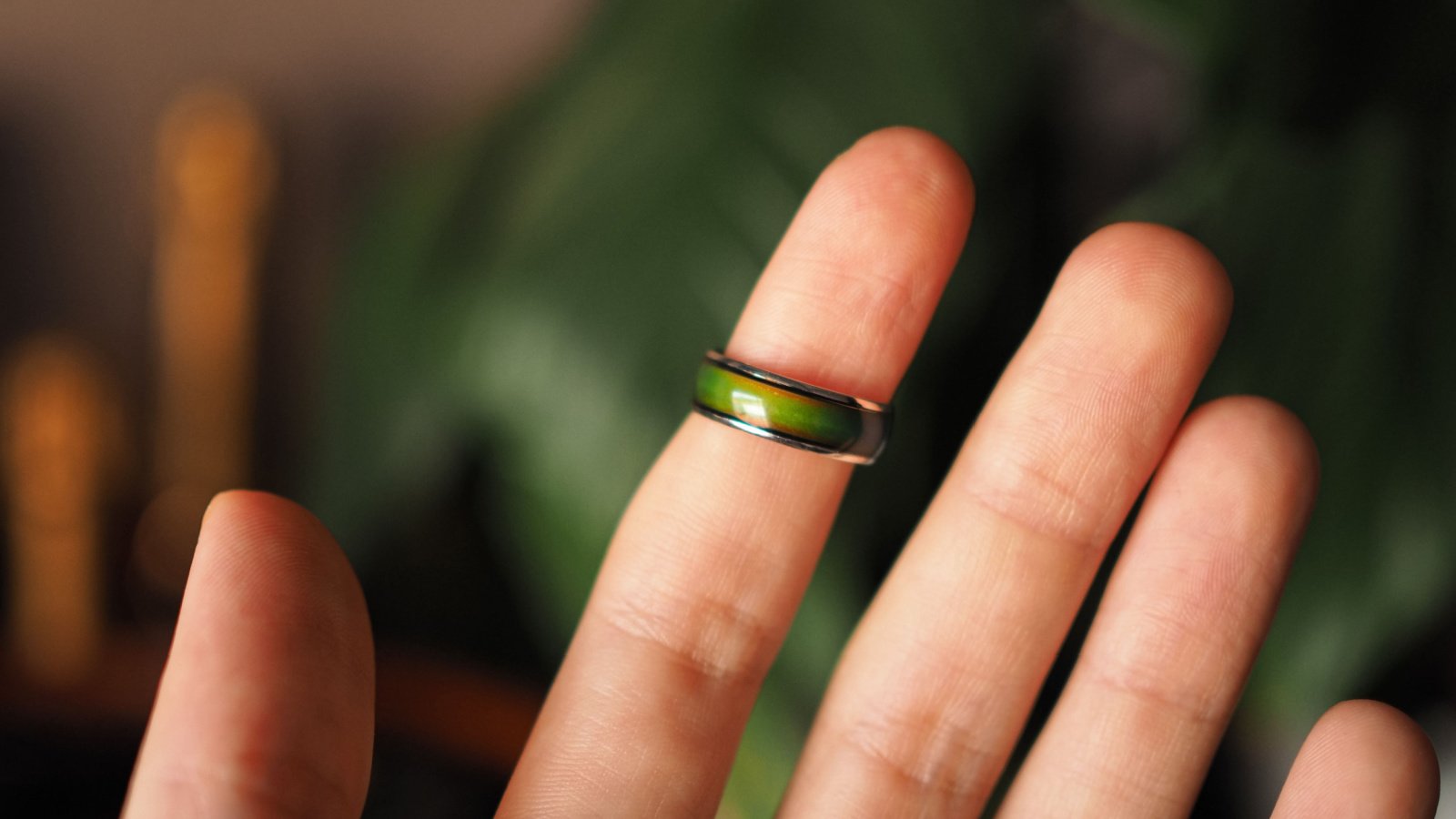 Green mood ring detail on the index finger of an open hand raulince shutterstock