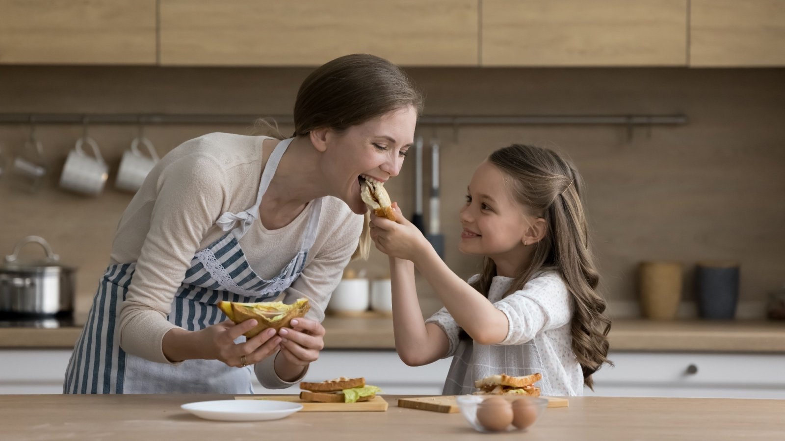 Joyful girl feeds mom a sandwich fizkes Shutterstock Joyful girl feeds mom a sandwich fizkes Shutterstock