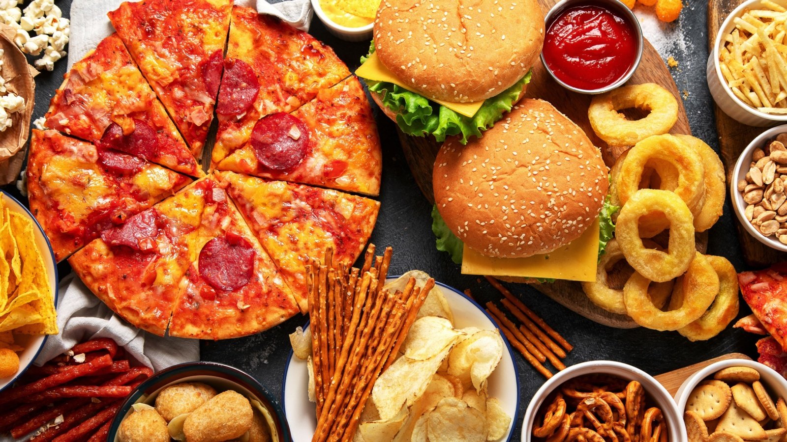 Junk food table of take out pizza french fries onion rings burgers and snacks trans fat fried buffet fast food Tatjana Baibakova Shutterstock