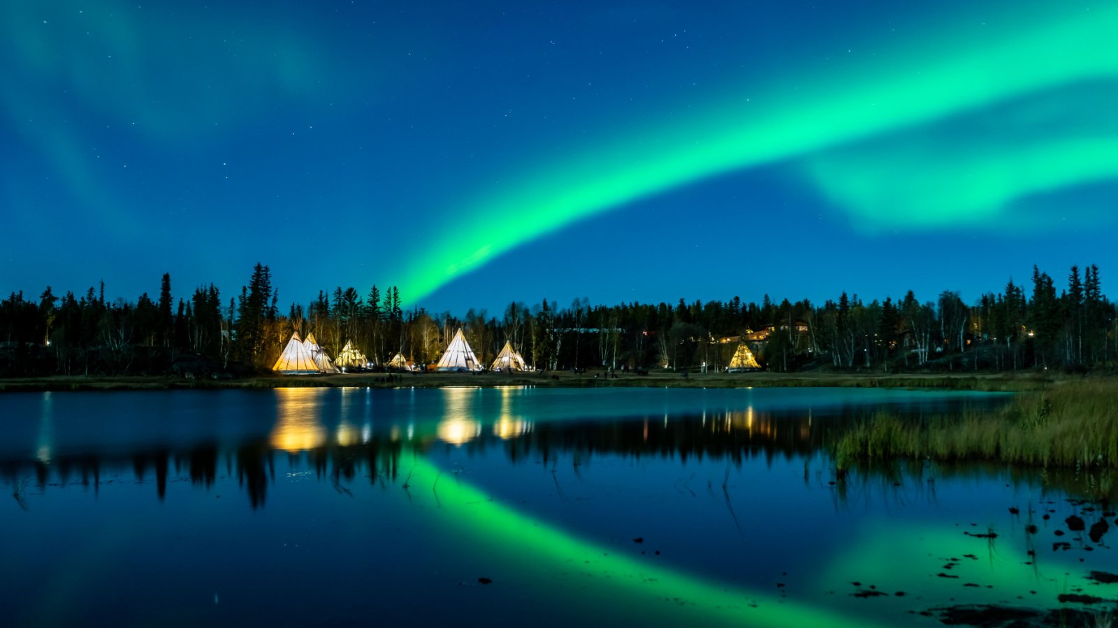 Light up Tipi (indian Tent) with water reflection during Aurora Borealis (Northern Light) at Yellow Knife, Canada LeeSensei Shutterstock