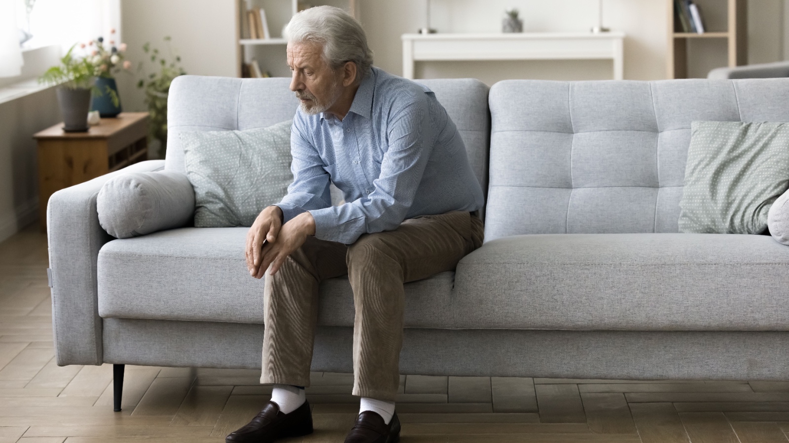 Lonely older man sitting on couch sad and coping with loss fizkes Shutterstock