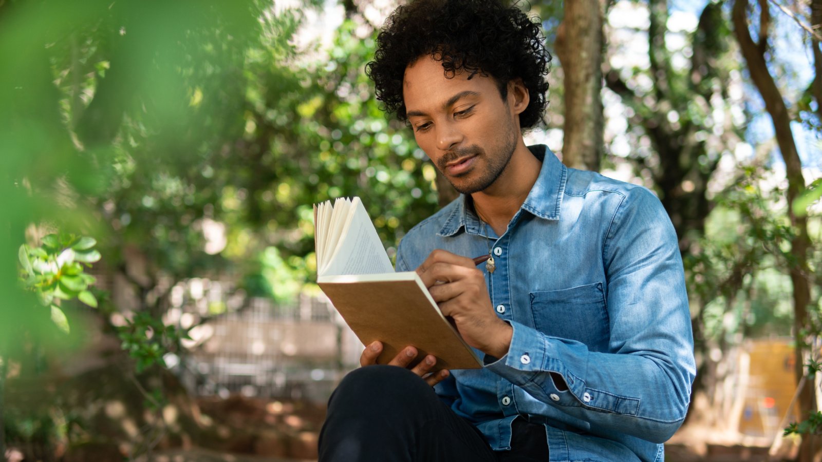 Male POC writing journaling nature self care reflection planning goals Vergani Fotografia Shutterstock