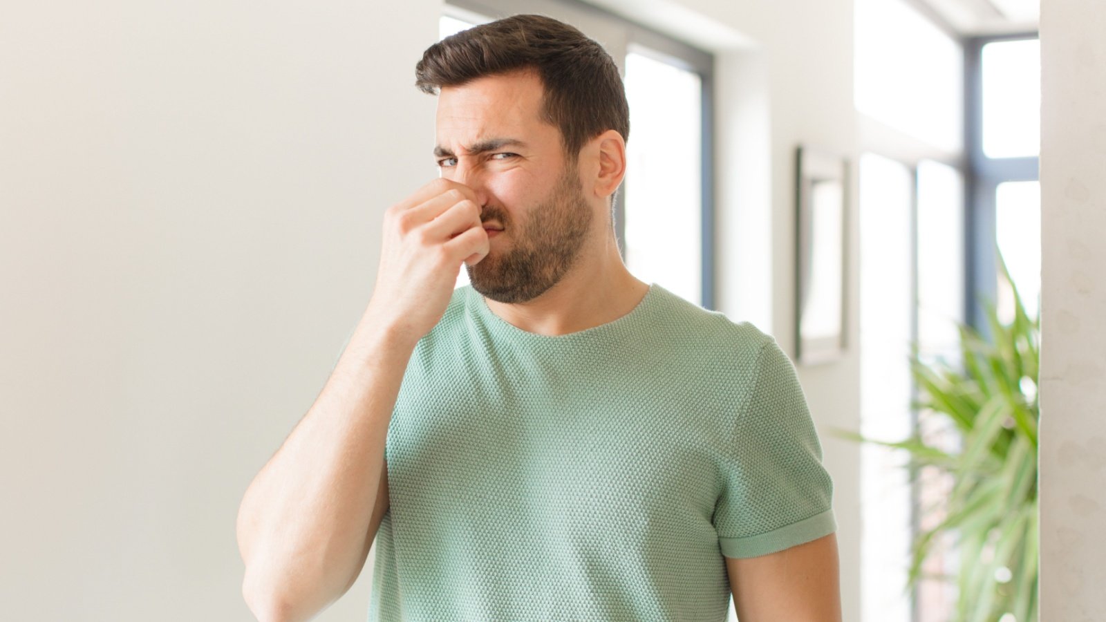 Male disgusted holding nose to avoid smelling a foul and unpleasant stench bad smell stink Kues Shutterstock