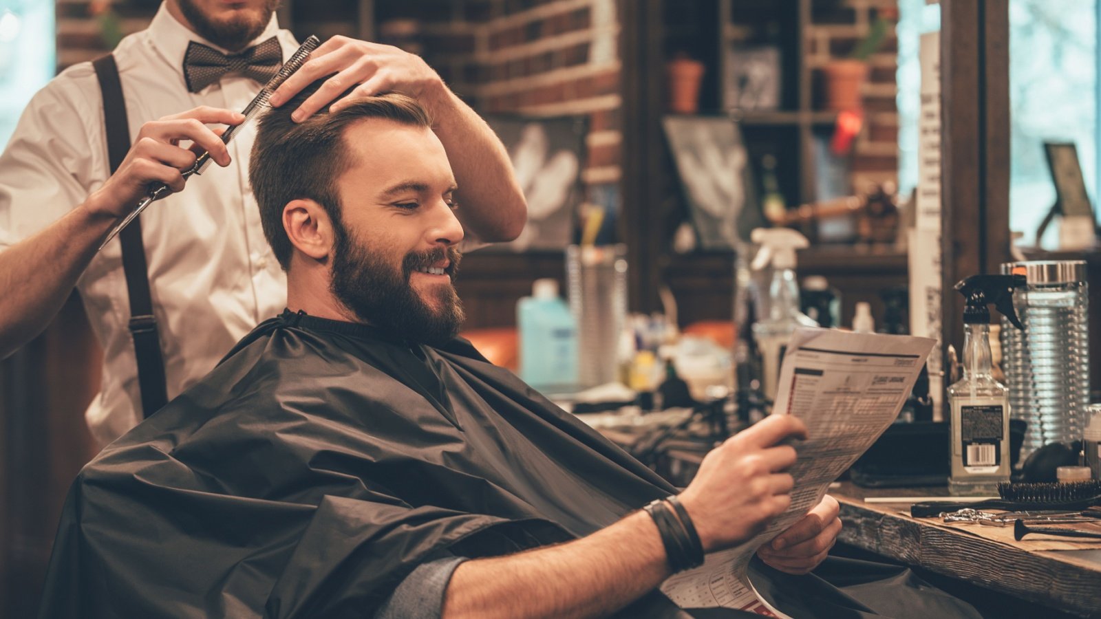 Male in a barbershop getting a haircut and reading a newspaper G Stock Studio Shutterstock