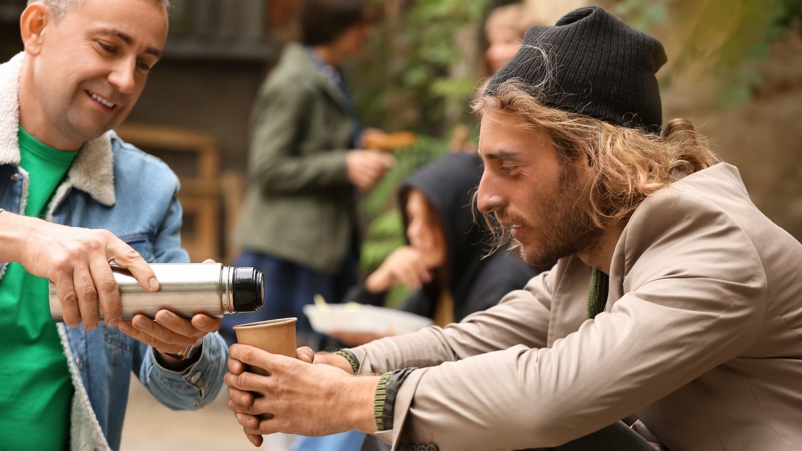 Male sharing water with homeless Pixel Shot Shutterstock