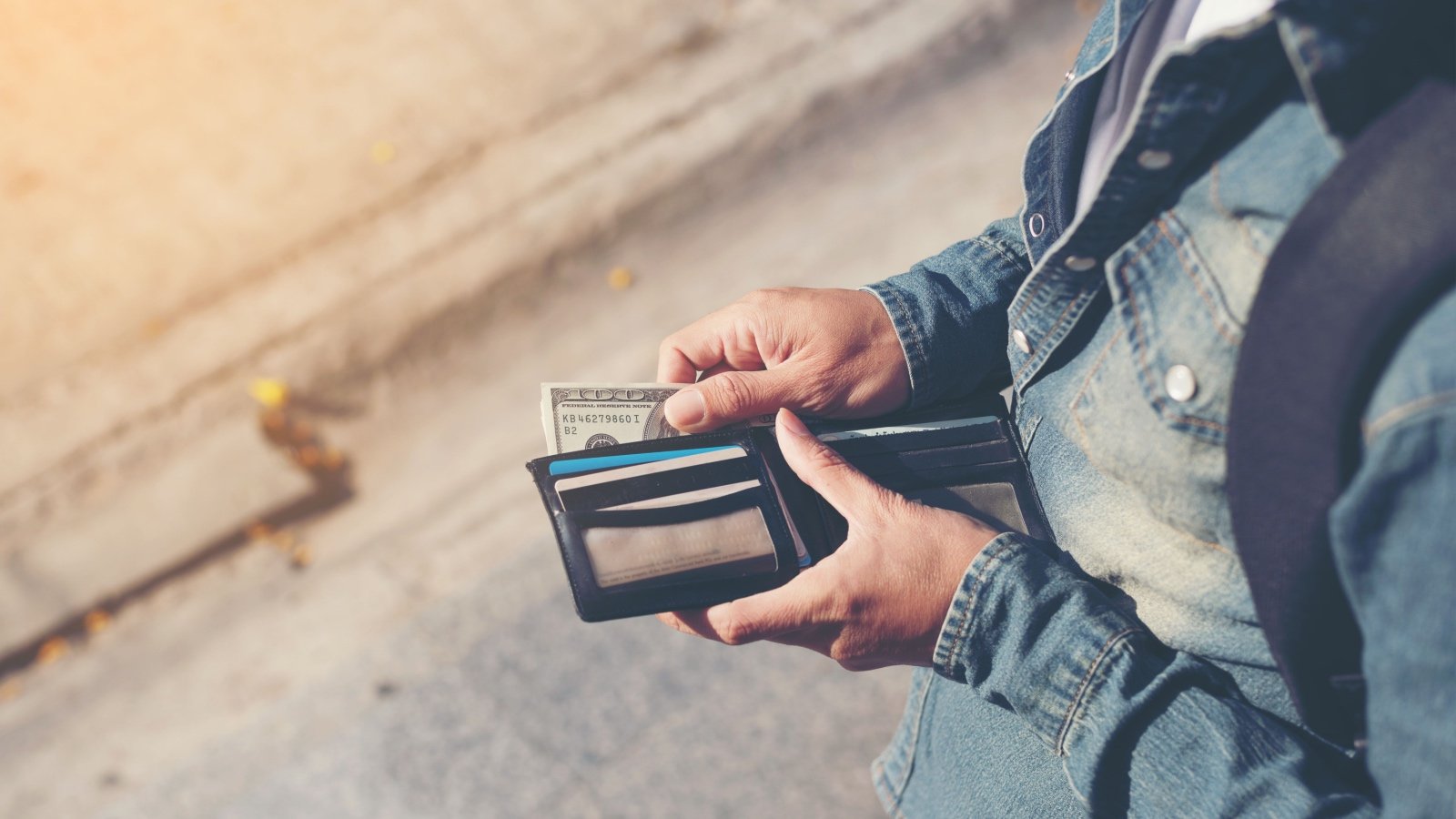 Man holding wallet with money and credit card boonchoke Shutterstock