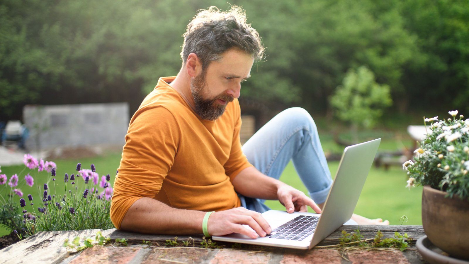 Mature male with laptop working outdoors in garden home office concept ground picture shutterstock