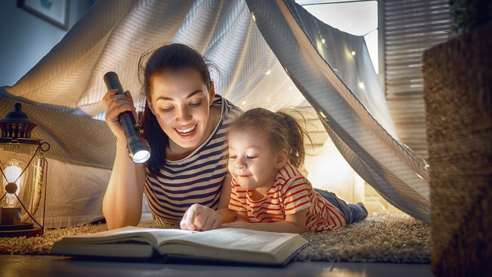 Mother daughter child tent flashlight read book Yuganov Konstantin Shutterstock