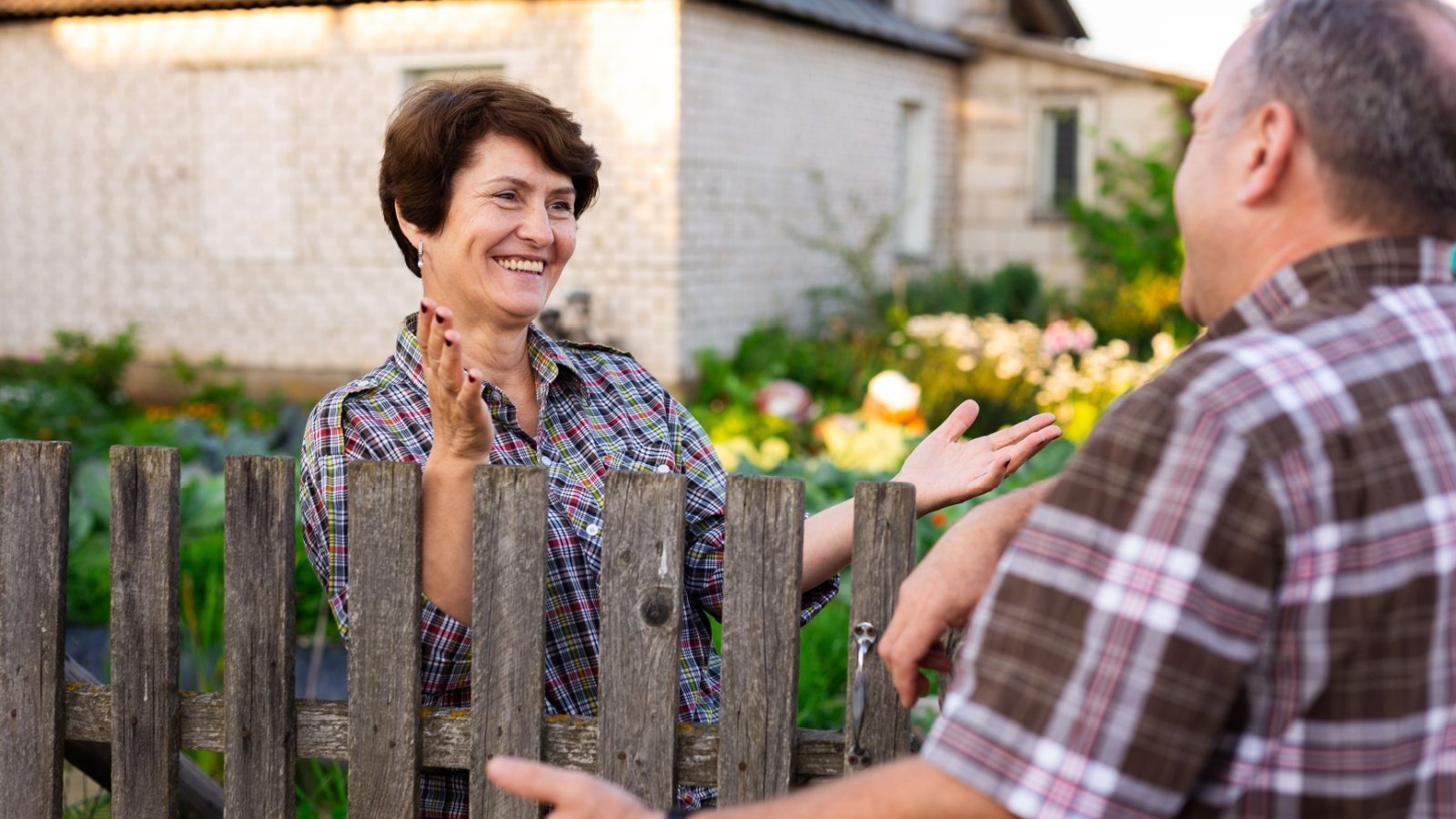 Neighbors talk chat over fence backyard community friends Caftor Shutterstock