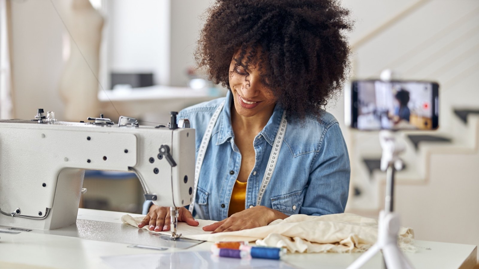 POC female seamstress sewing clothes shooting video for blog Friends Stock Shutterstock