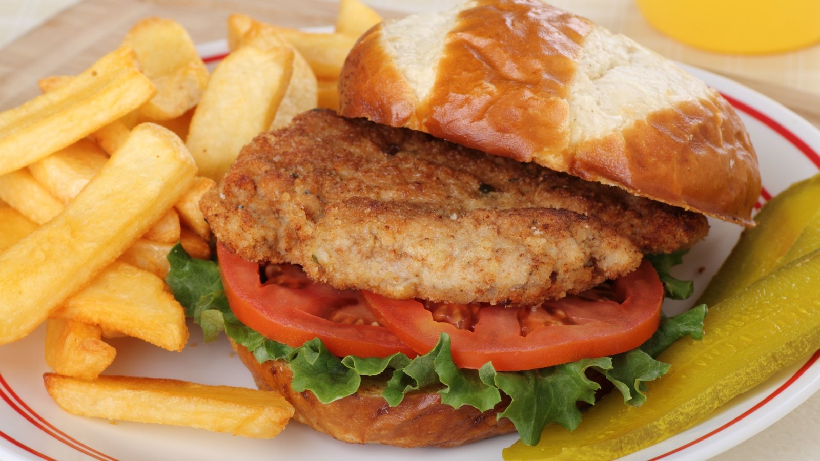 Pork tenderloin pickle lettuce and tomato sandwich on a bun with french fries Charles Brutlag Shutterstock