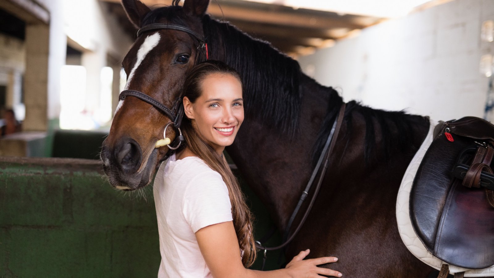 Portrait of smiling female jockey standing by horse in stable wavebreakmedia shutterstock