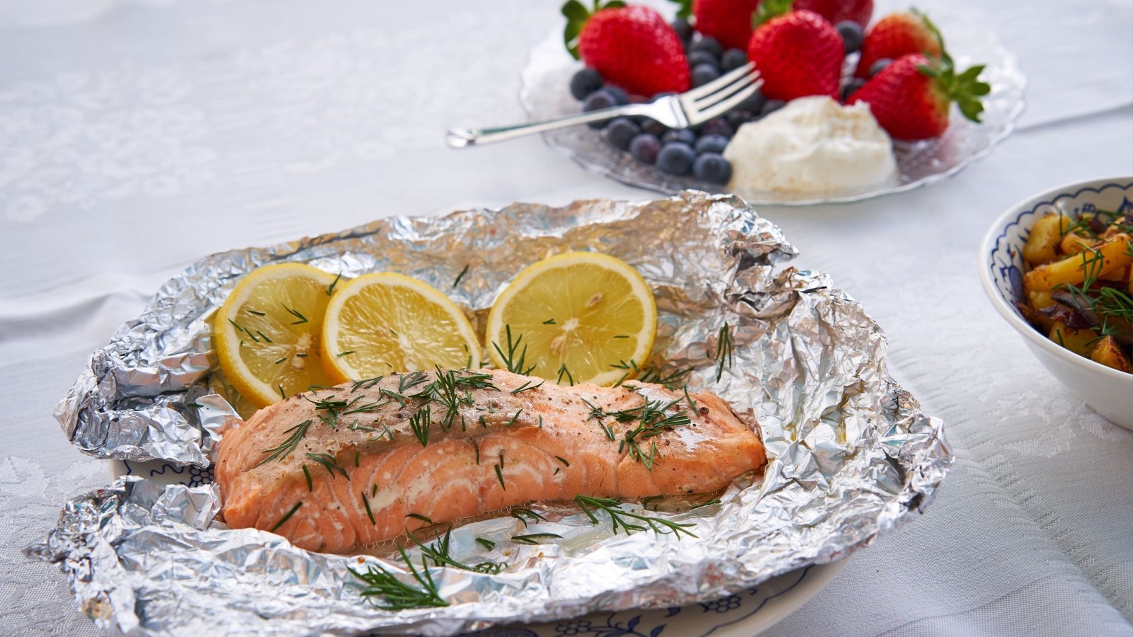 Salmon baked in foil with lemon and dill with strawberries blueberries cream and potatoes Jan Danek jdm.foto Shutterstock