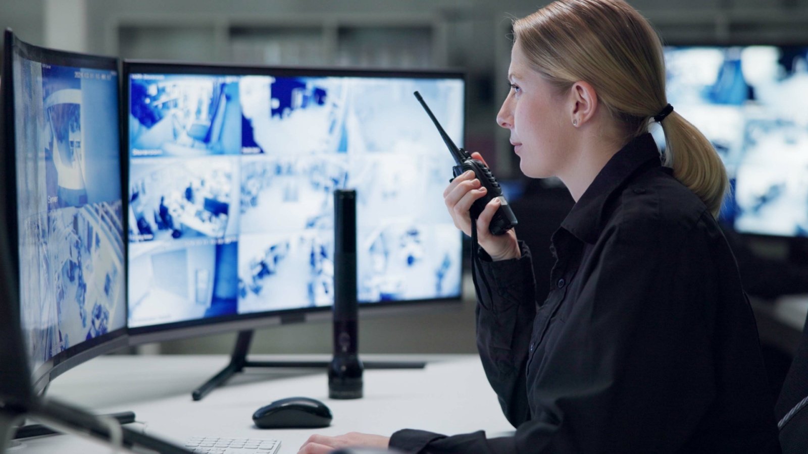 Security guard and woman with radio control room monitors secret service PeopleImagescom Yuri A Shutterstock