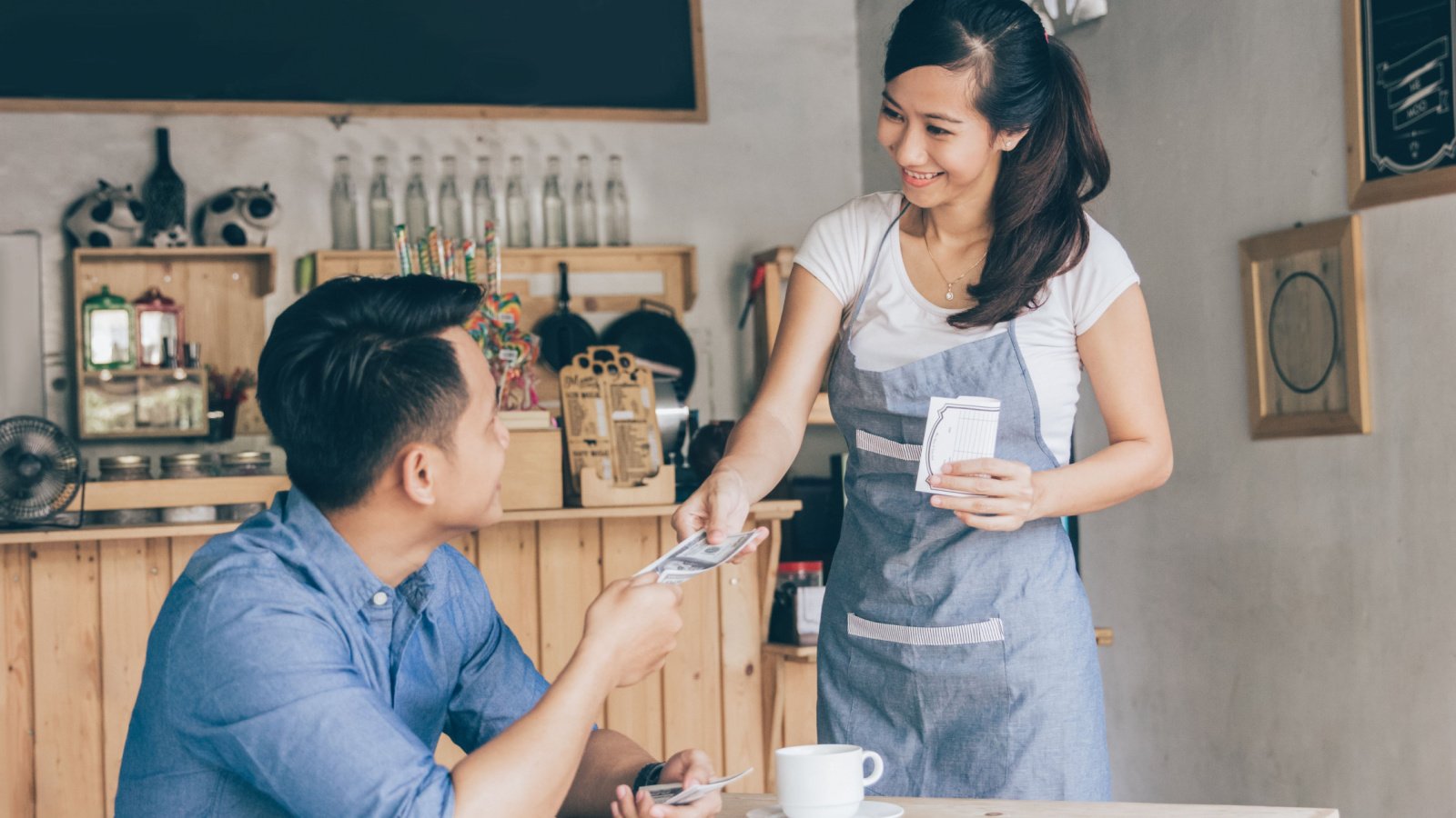 Smiling customer paying by cash at the coffee shop Odua Images Shutterstock