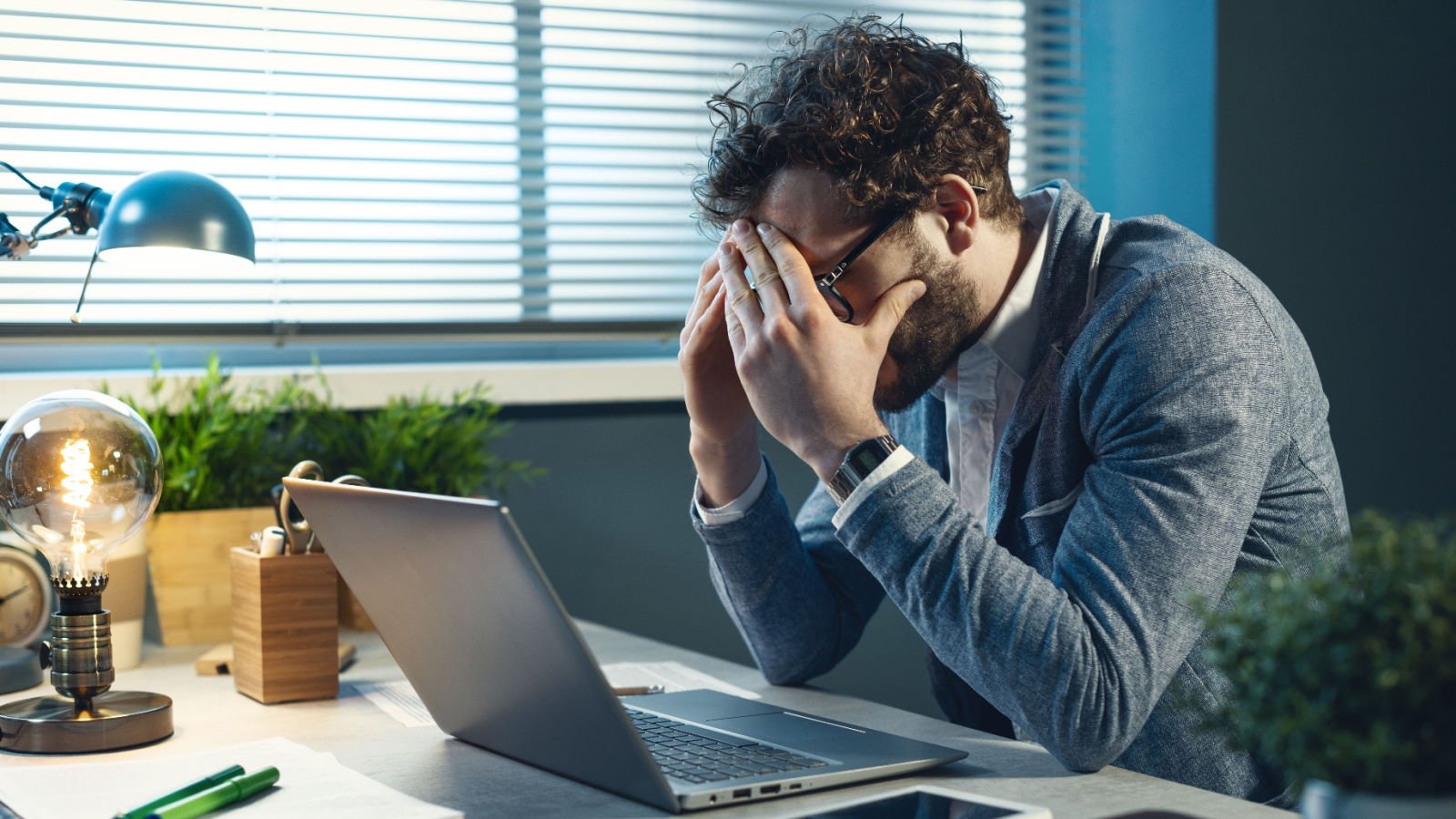 Stressed young businessman sitting at office desk computer jobs work stock asso shutterstock