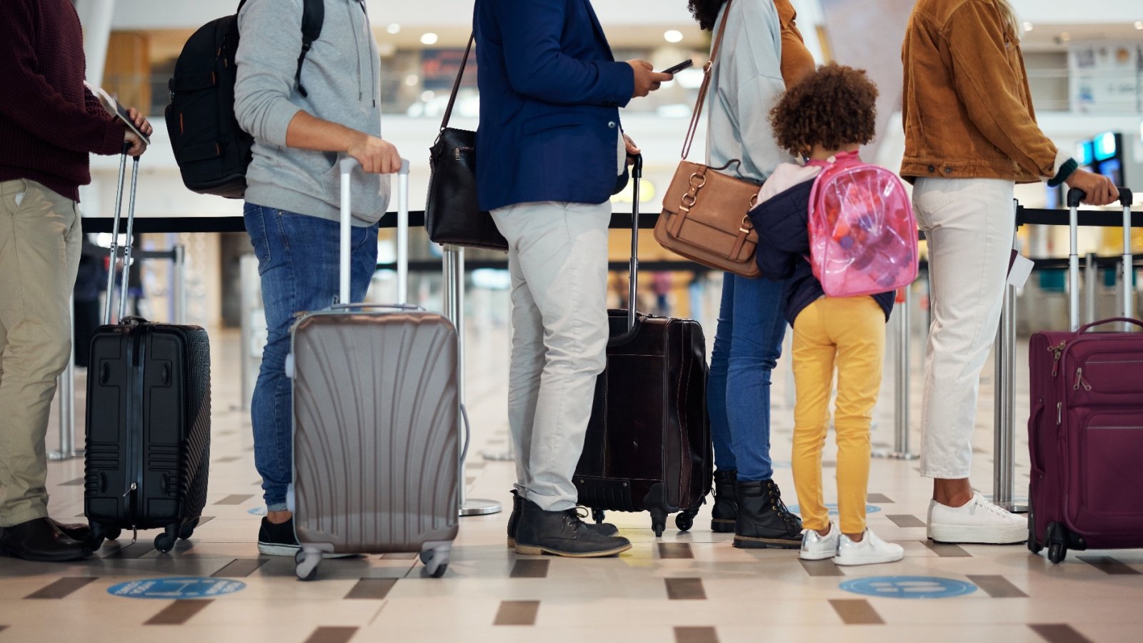 Travel standing in line at the airport with suitcases PeopleImagescom Yuri A Shutterstock