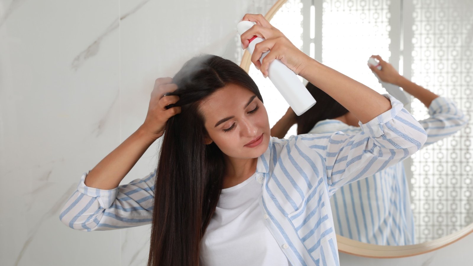 Woman applying hair spray and dry shampoo New Africa Shutterstock