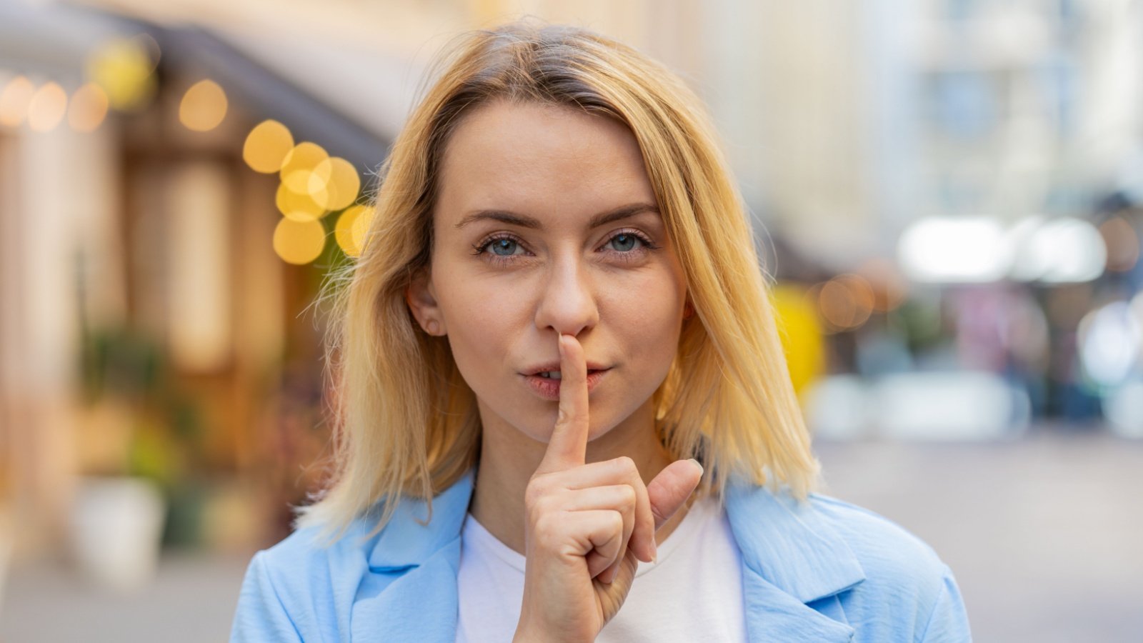 Woman hold finger to lips be quiet shh too loud whisper secret hush gossip Andrii Iemelianenko Shutterstock