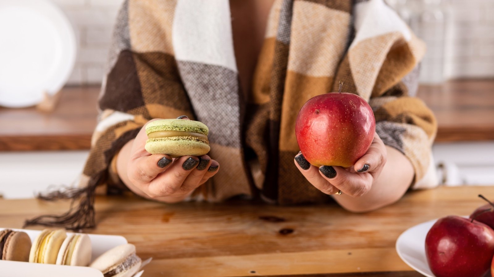 Woman holding macaroon and apple Akifyeva S Shutterstock
