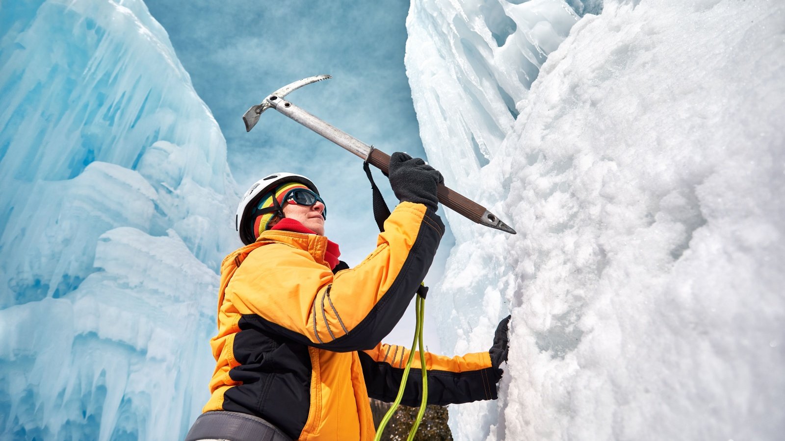 Woman is climbing frozen waterfall with ice axe Pikoso.kz Shutterstock