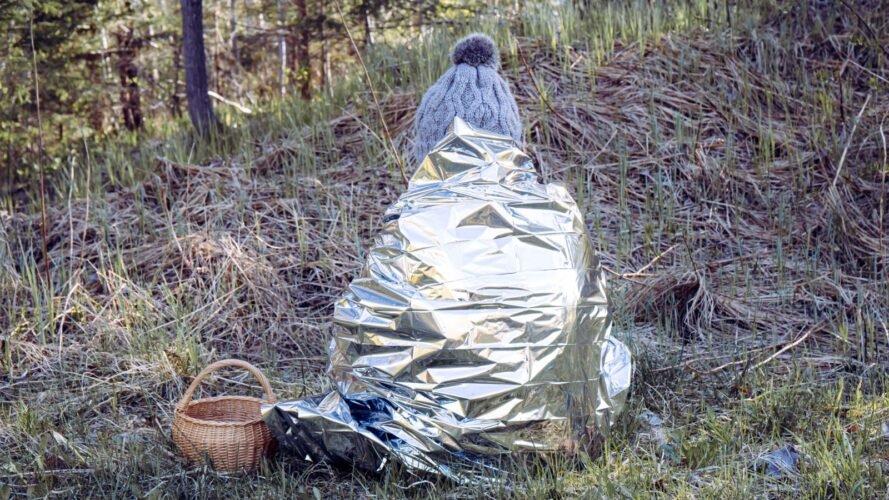 Woman is lost in the woods first aid emergency blanket to prevent hypothermia and body heat loss space blanket FotoHelin Shutterstock