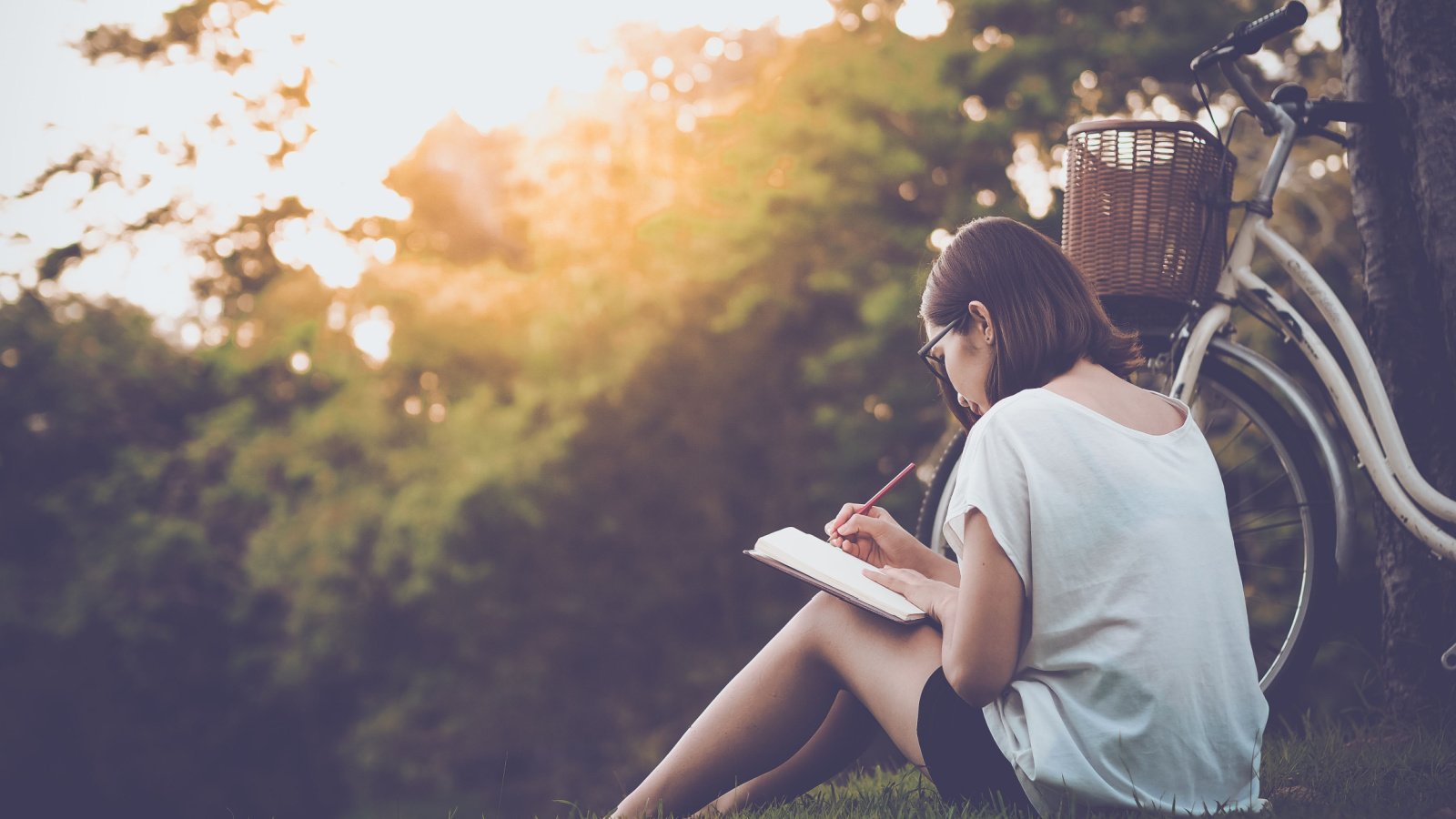 Woman journaling outdoors bike self care reflection meditation Teechai Shutterstock