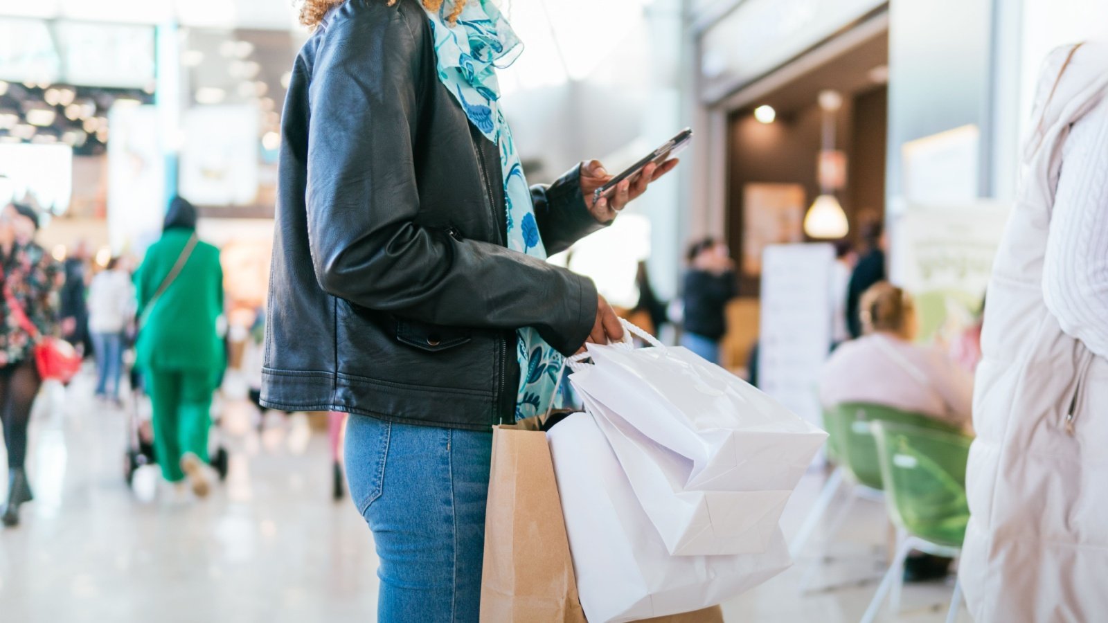 Woman shopping and using phone text call social media standing in line deals discount Miguel Paricio Shutterstock