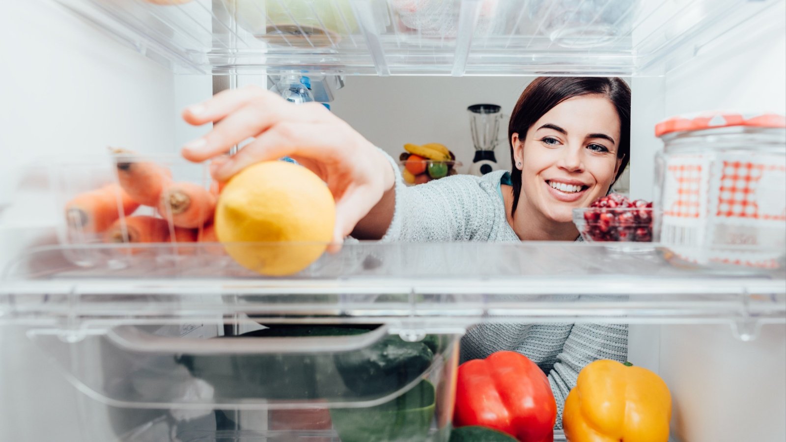 Woman taking lemon fruit out of refrigerator fridge healthy vegetables kitchen cooking home Stokkete Shutterstock