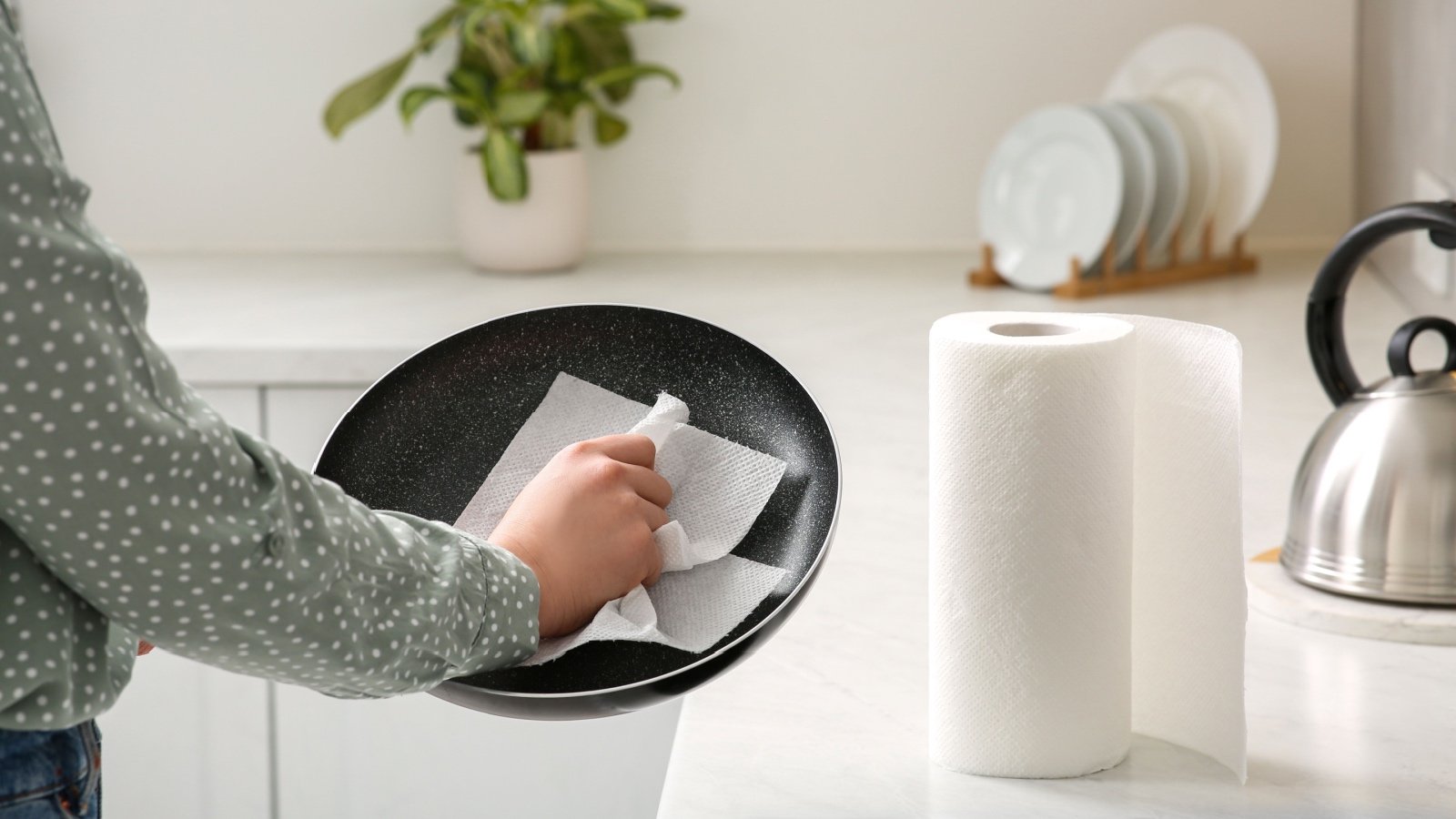 Woman wiping frying pan with paper towel in kitchen New Africa Shutterstock