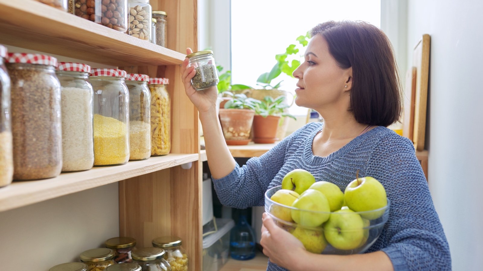 Woman with bowl of green apples in pantry VH studio Shutterstock