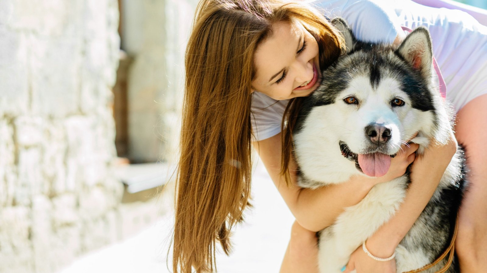 Young long hair woman hugging her dog alaskan malamute Iryna Inshyna Shutterstock