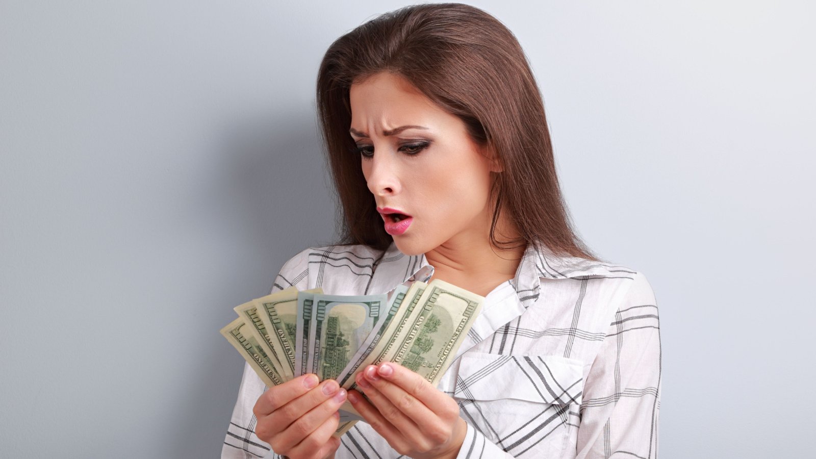 Young woman looking and counting her salary and thinking how little money she have earned money fan anastasia vishn shutterstock