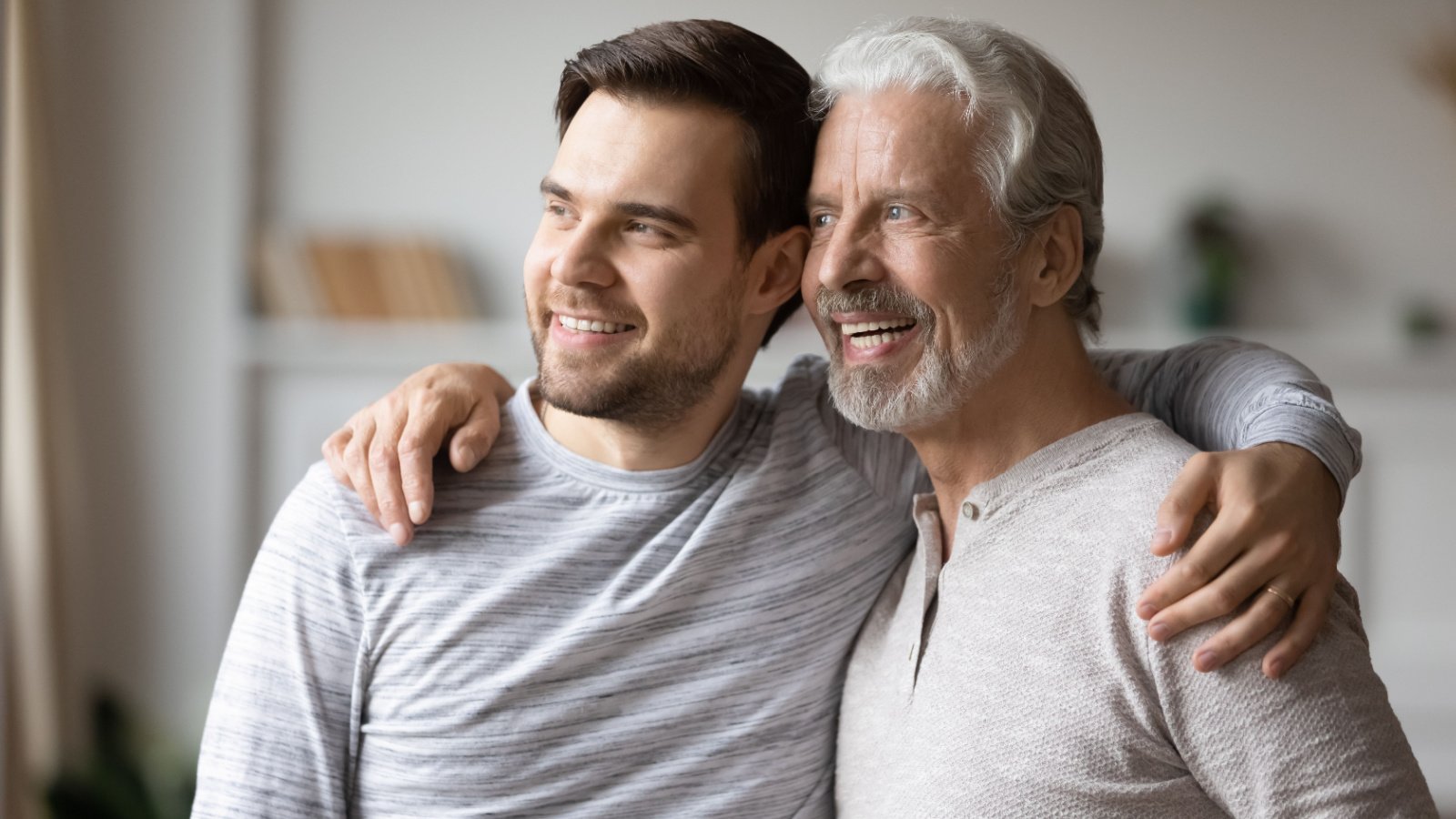 adult senior father son embracing staring out window at home