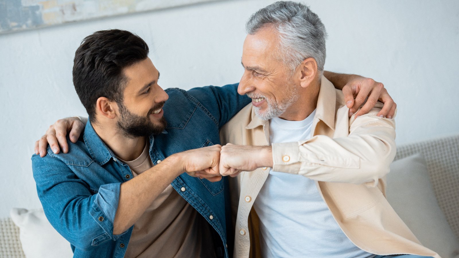 cheerful retired father senior fist bumping with happy bearded son at home lightfield studios shutterstock