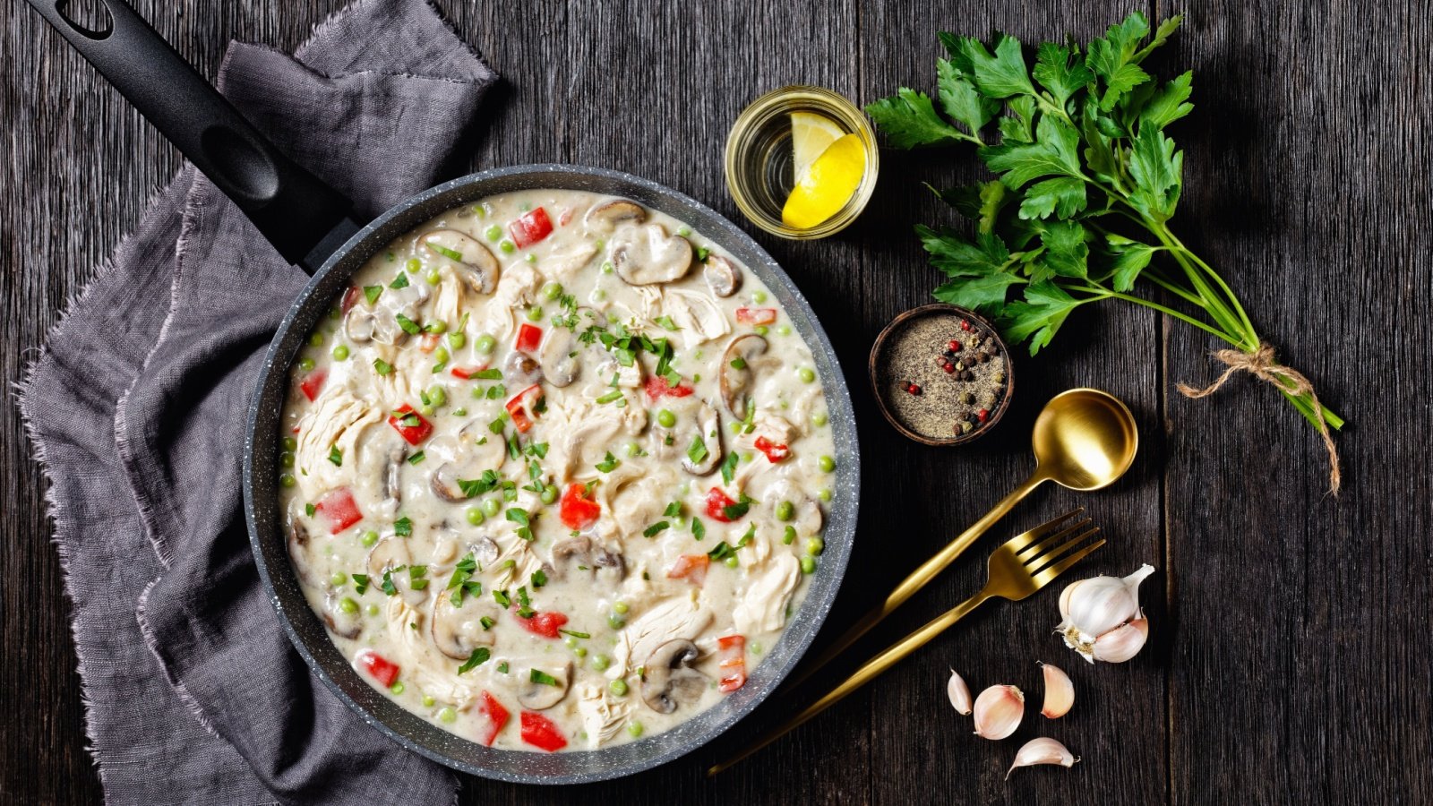 chicken a la king cooked breast of chicken in a cream sauce with mushrooms green peas and peppers in a saucepan on a wooden table from my point of view Shutterstock